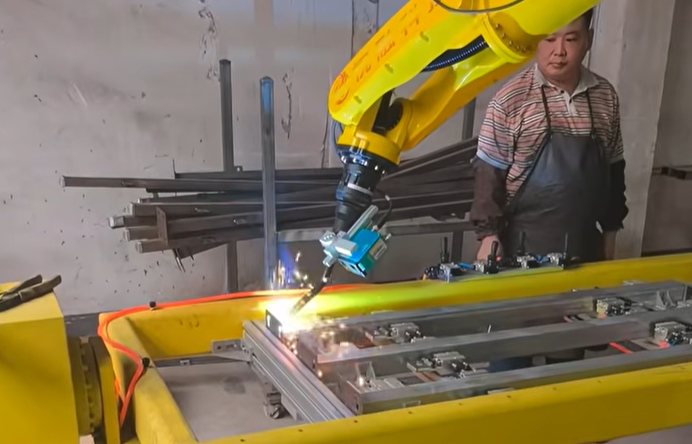 XARP XP1440-15W robot performing laser-assisted MIG/MAG welding on a fabricated steel frame at a customer site